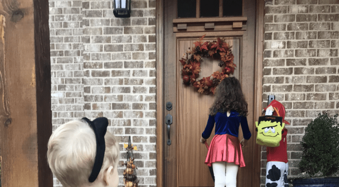 Three kids in costumes on a front porch.