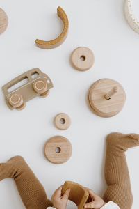Beige clothed child playing with beige wooden toys